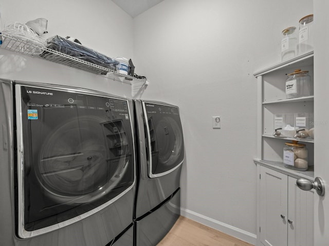 clothes washing area featuring light wood finished floors, baseboards, laundry area, and washer and clothes dryer