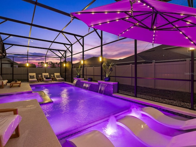 pool at dusk with glass enclosure, a patio, a fenced backyard, and a fenced in pool