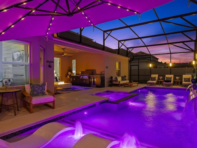 view of swimming pool with a lanai, exterior kitchen, an outdoor hangout area, a patio, and a ceiling fan