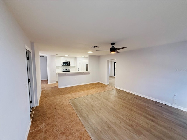 unfurnished living room with light wood-type flooring and ceiling fan