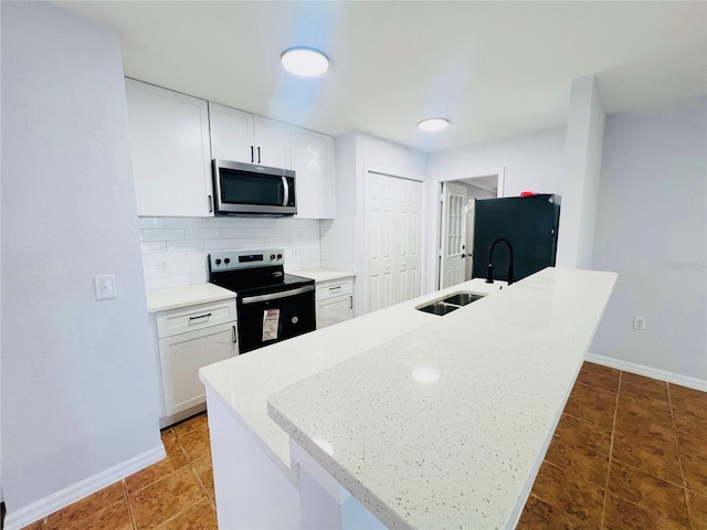 kitchen featuring white cabinetry, sink, light stone counters, backsplash, and appliances with stainless steel finishes