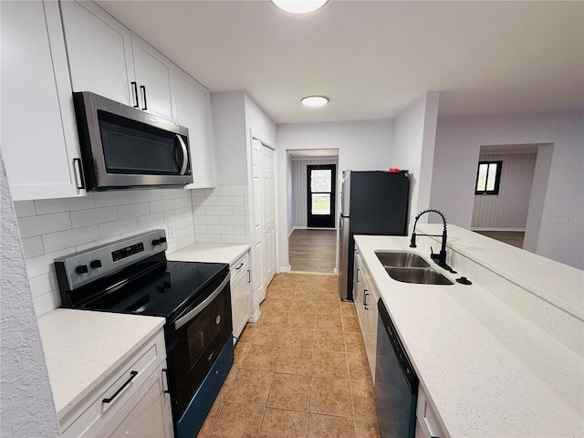 kitchen featuring light stone countertops, appliances with stainless steel finishes, white cabinetry, and sink