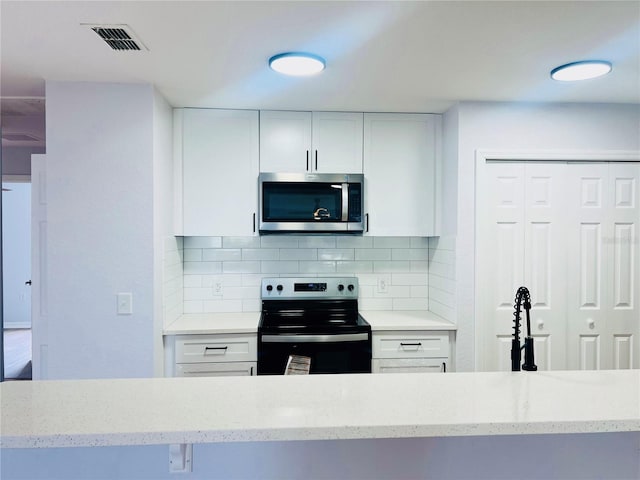 kitchen with light stone countertops, white cabinetry, appliances with stainless steel finishes, and tasteful backsplash