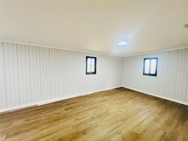 interior space featuring hardwood / wood-style flooring, a wealth of natural light, ornamental molding, and wood walls