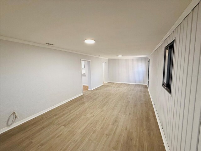 unfurnished room featuring wood walls, light hardwood / wood-style flooring, and ornamental molding