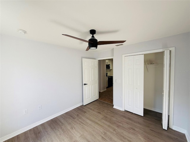 unfurnished bedroom featuring ceiling fan, a closet, and wood-type flooring