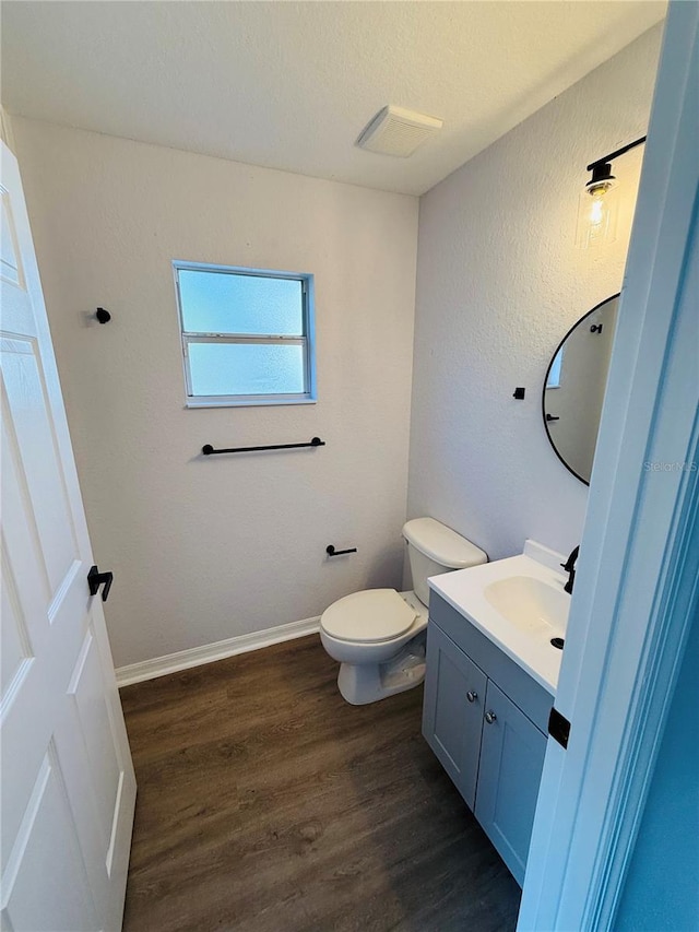 bathroom with hardwood / wood-style flooring, vanity, toilet, and a textured ceiling