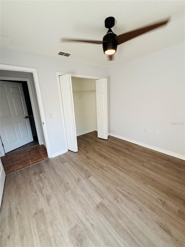 unfurnished bedroom featuring ceiling fan, light wood-type flooring, and a closet