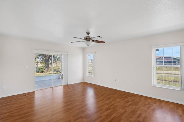 empty room featuring hardwood / wood-style floors, plenty of natural light, ceiling fan, and a textured ceiling