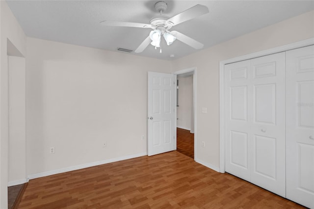 unfurnished bedroom featuring ceiling fan, a closet, and hardwood / wood-style flooring