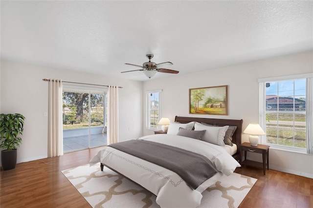 bedroom with ceiling fan, dark hardwood / wood-style flooring, access to exterior, and multiple windows