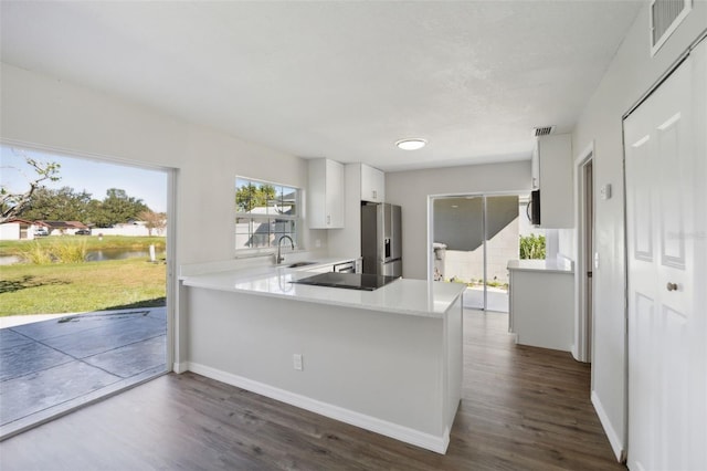 kitchen with white cabinetry, sink, dark hardwood / wood-style flooring, stainless steel refrigerator with ice dispenser, and kitchen peninsula