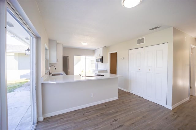 kitchen with kitchen peninsula, white cabinets, stainless steel appliances, and a healthy amount of sunlight