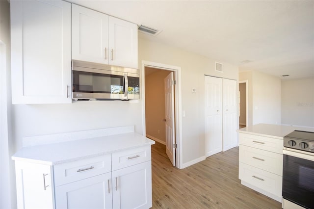 kitchen featuring stainless steel appliances, white cabinetry, and light hardwood / wood-style floors