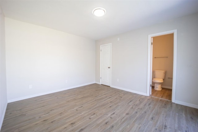 unfurnished bedroom with ensuite bathroom, light wood-type flooring, and a closet