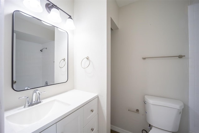 bathroom with vanity, toilet, and tiled shower