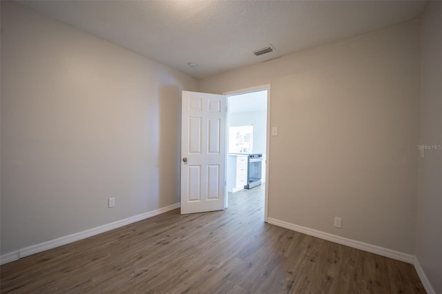 unfurnished room with wood-type flooring and a textured ceiling