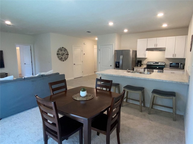 dining space featuring light carpet and sink