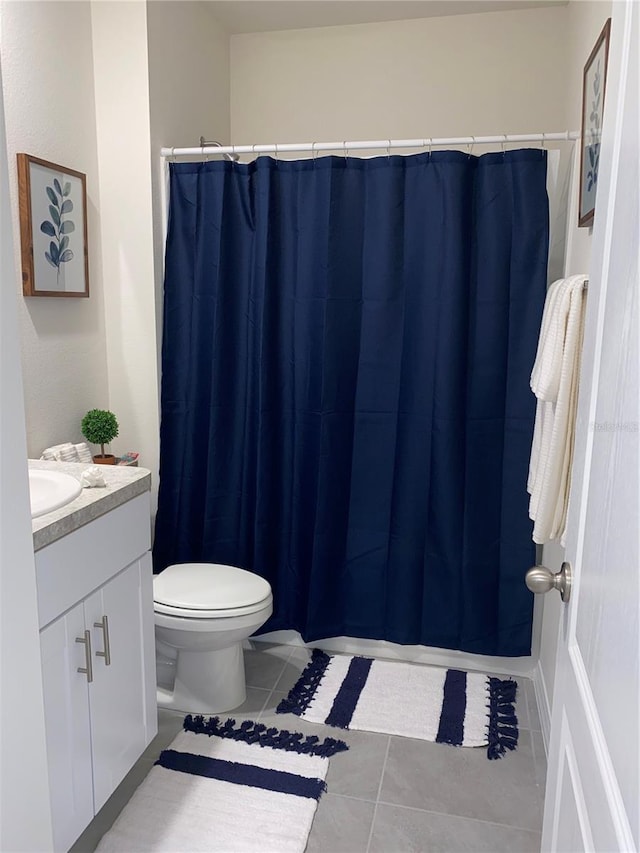 bathroom with toilet, vanity, tile patterned floors, and walk in shower