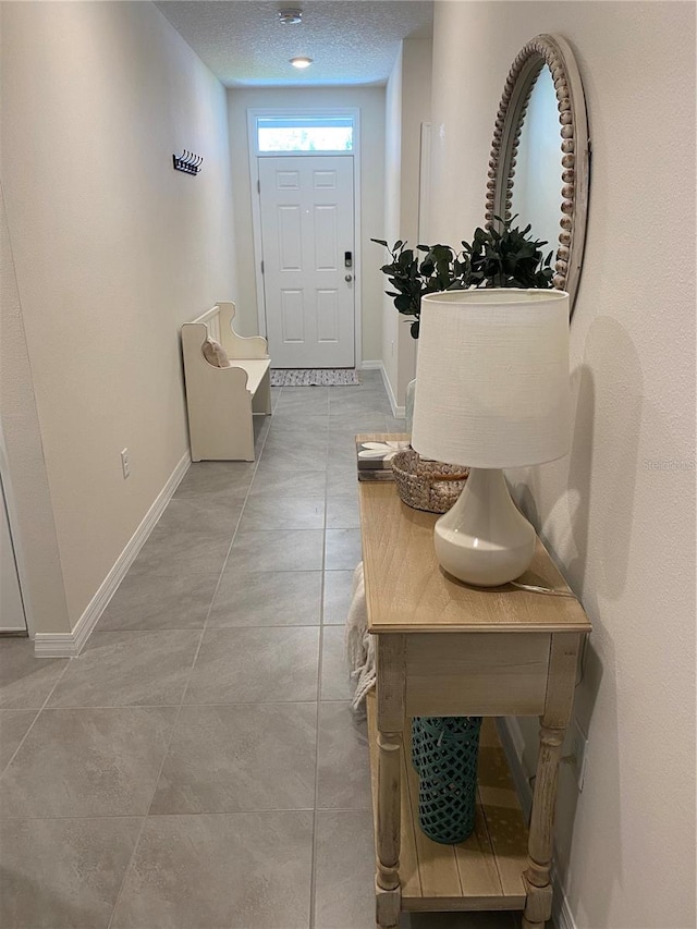 doorway to outside featuring tile patterned flooring and a textured ceiling