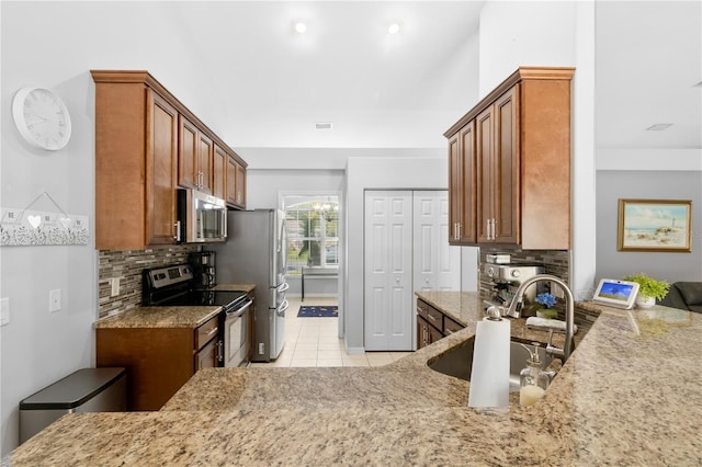 kitchen with sink, light stone counters, decorative backsplash, light tile patterned floors, and appliances with stainless steel finishes