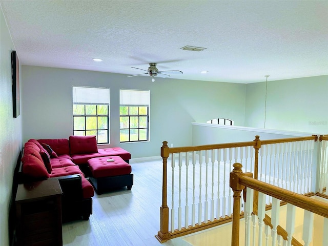 interior space featuring a textured ceiling, light hardwood / wood-style flooring, and ceiling fan