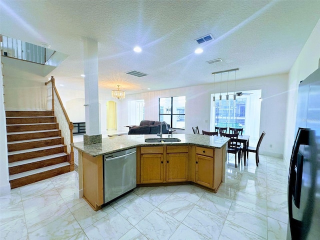 kitchen featuring sink, hanging light fixtures, a textured ceiling, light stone counters, and stainless steel appliances