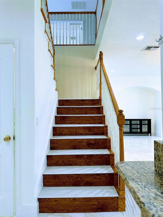 staircase featuring a textured ceiling