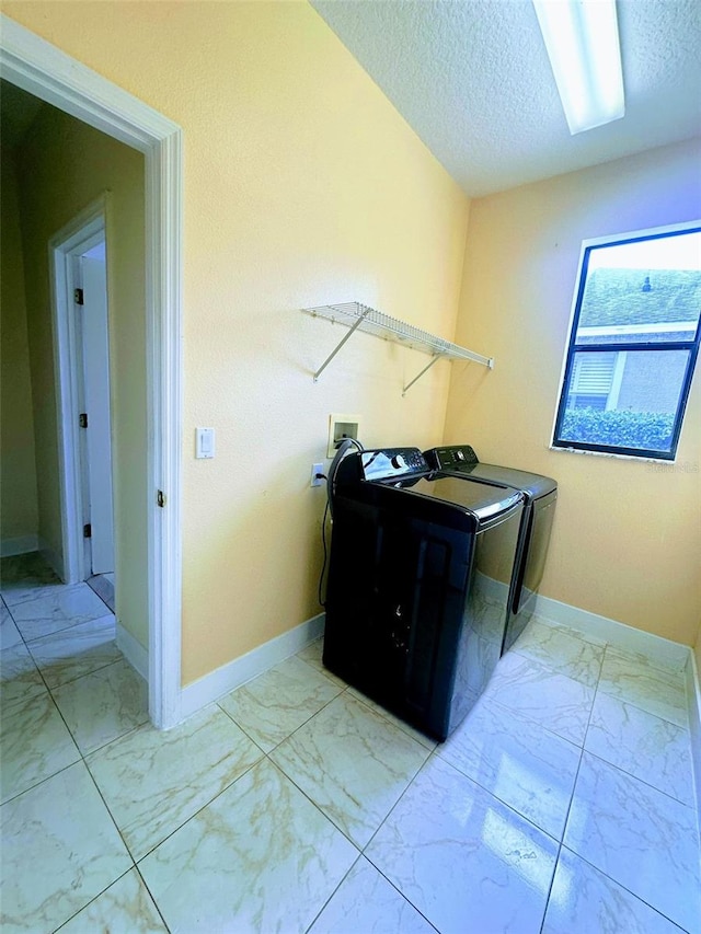 clothes washing area with a textured ceiling and washer and clothes dryer