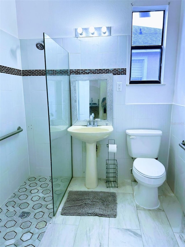 bathroom featuring tiled shower, toilet, and tile walls