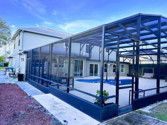 view of property exterior with a lanai, a patio, and a pool