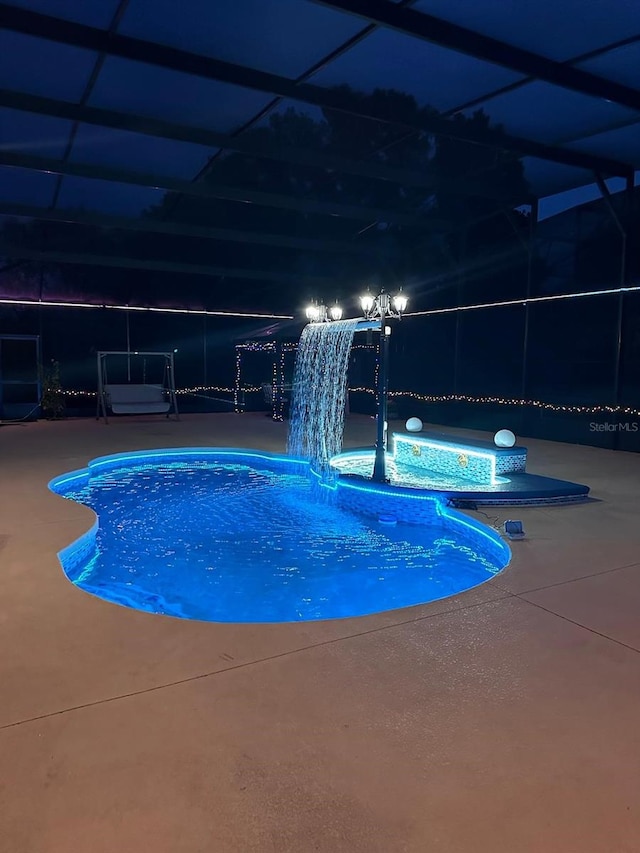 view of swimming pool featuring pool water feature, a lanai, and a patio