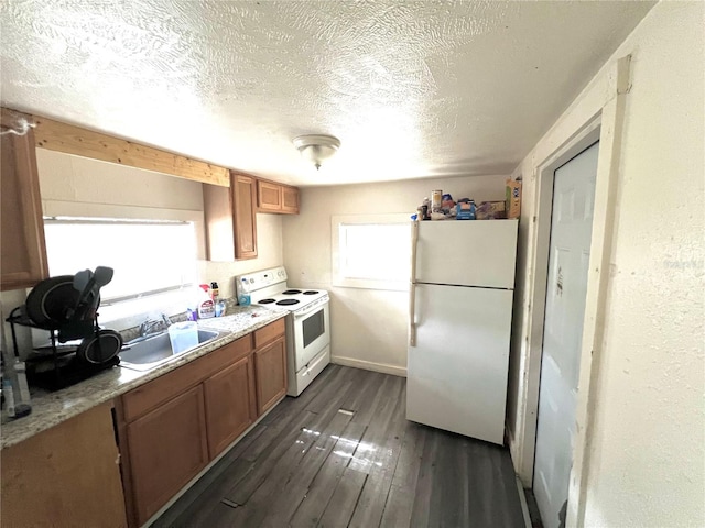 kitchen featuring white appliances, sink, dark hardwood / wood-style floors, light stone countertops, and a textured ceiling