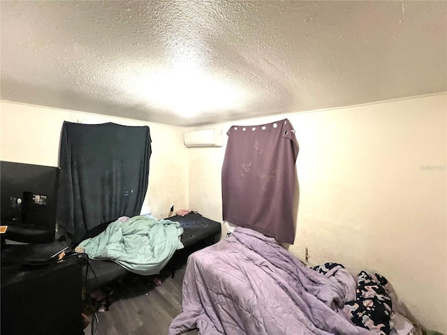 bedroom with wood-type flooring, a textured ceiling, and a wall mounted AC