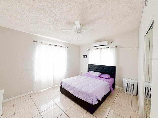 tiled bedroom featuring a wall mounted AC, ceiling fan, a closet, and a textured ceiling