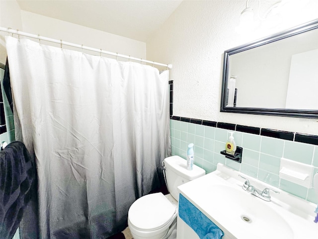 bathroom featuring vanity, tile walls, and toilet