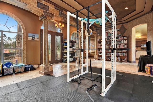 exercise room featuring decorative columns and tile patterned floors