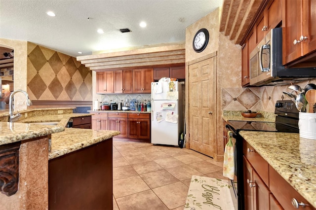 kitchen with black range with electric stovetop, sink, light stone counters, white fridge, and a textured ceiling