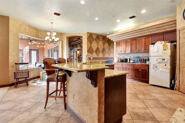 kitchen with pendant lighting, white fridge, a textured ceiling, and an inviting chandelier