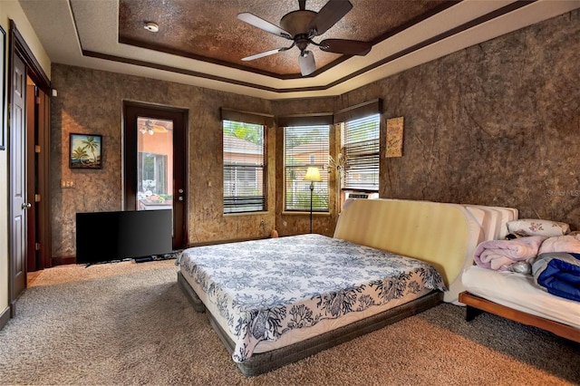 carpeted bedroom with a raised ceiling and ceiling fan