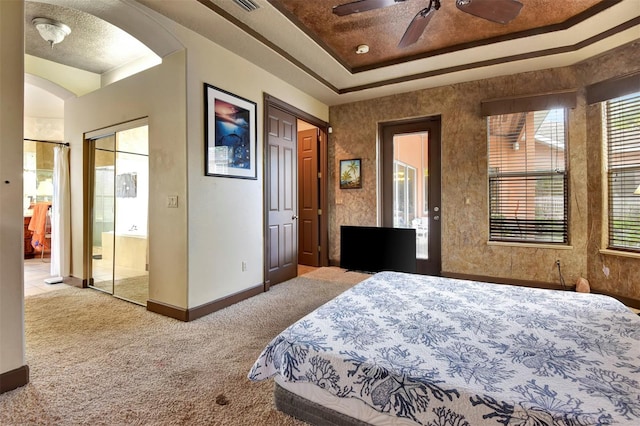 carpeted bedroom with a raised ceiling, ceiling fan, and a textured ceiling