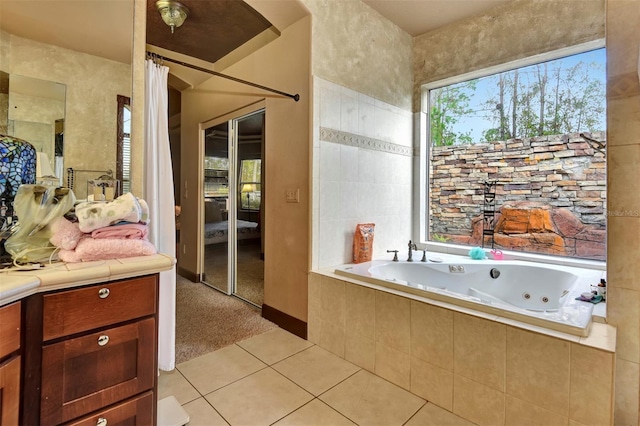 bathroom featuring tile patterned floors, vanity, and tiled bath