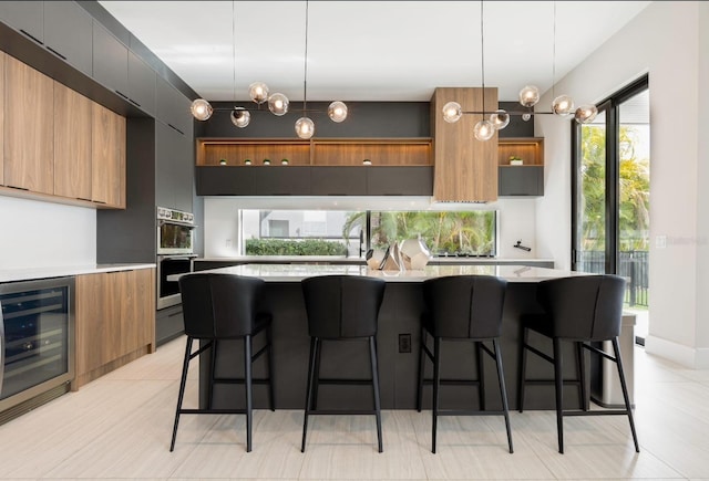 kitchen featuring wine cooler, a breakfast bar, a center island, and pendant lighting