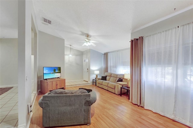 living room featuring hardwood / wood-style floors, ceiling fan, lofted ceiling, and a textured ceiling