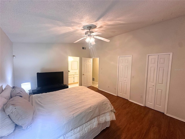 bedroom with multiple closets, ceiling fan, dark wood-type flooring, lofted ceiling, and a textured ceiling