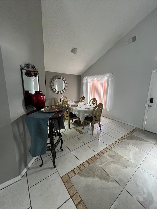 dining room with a textured ceiling and vaulted ceiling