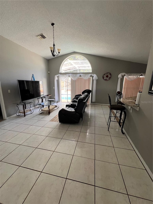 living room with a notable chandelier, light tile patterned flooring, a textured ceiling, and vaulted ceiling