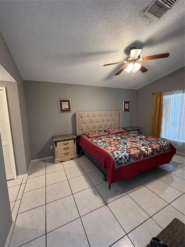 bedroom with ceiling fan, light tile patterned floors, and a textured ceiling