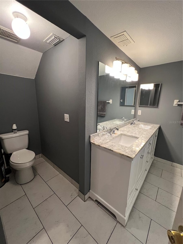 bathroom with a textured ceiling, vanity, and vaulted ceiling