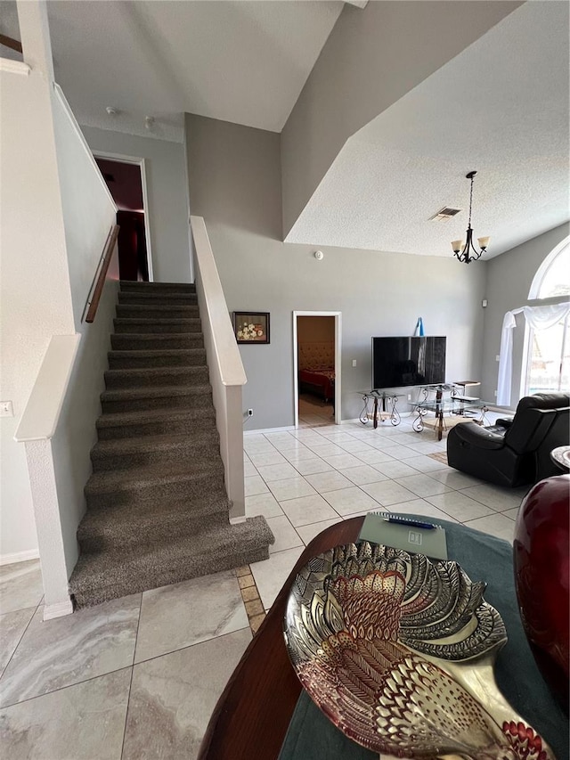 staircase featuring tile patterned flooring, a textured ceiling, and an inviting chandelier